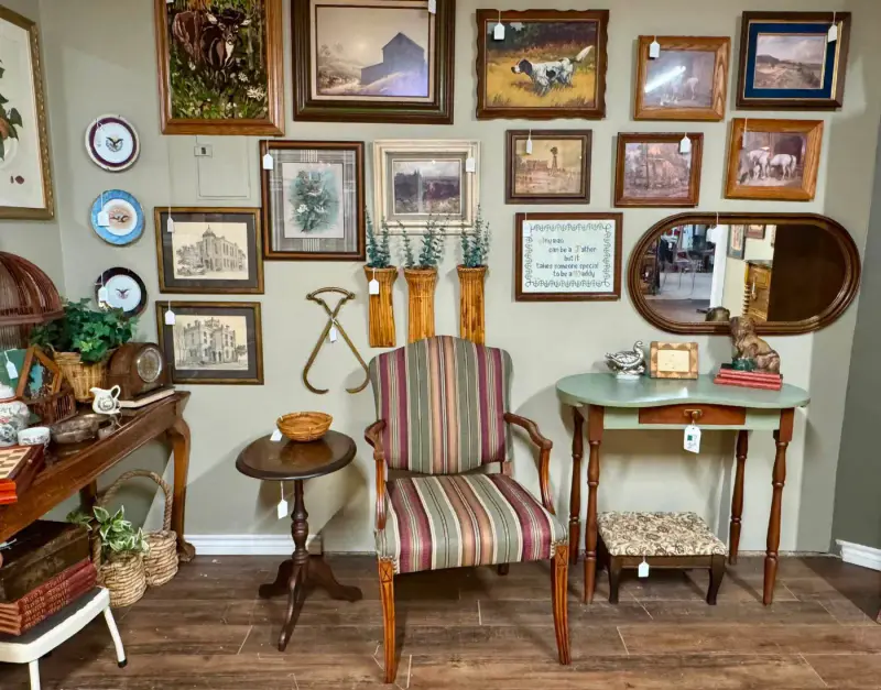 A reading corner in the booth: a striped chair, a small table and a wall of framed art