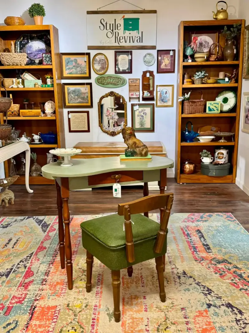 Kelli's booth at Blue Willow: a sage vanity and green chair on a colorful rug under the Style Revival sign