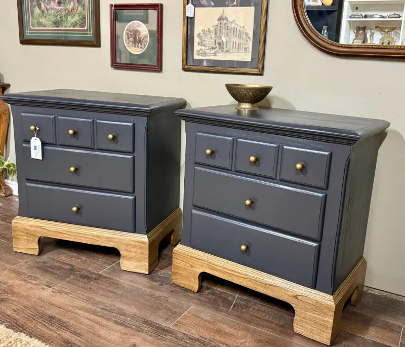 Pair of navy nightstands with brass knobs on natural wood plinth bases