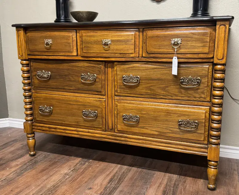 Oak dresser with turned spindle columns, a black top and brass bail pulls