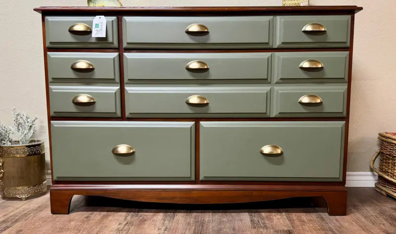 Nine-drawer dresser with sage green drawers, a cherry top and brass cup pulls